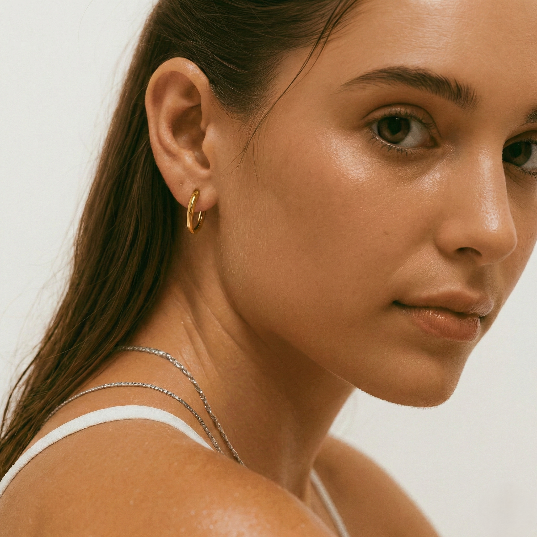 Close-up of a woman wearing a gold-plated hoop earring