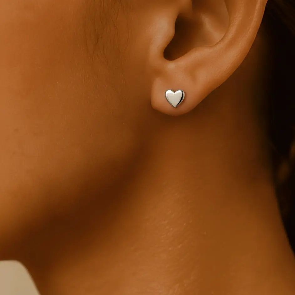 Waterproof silver heart studs earring on a women's ear.