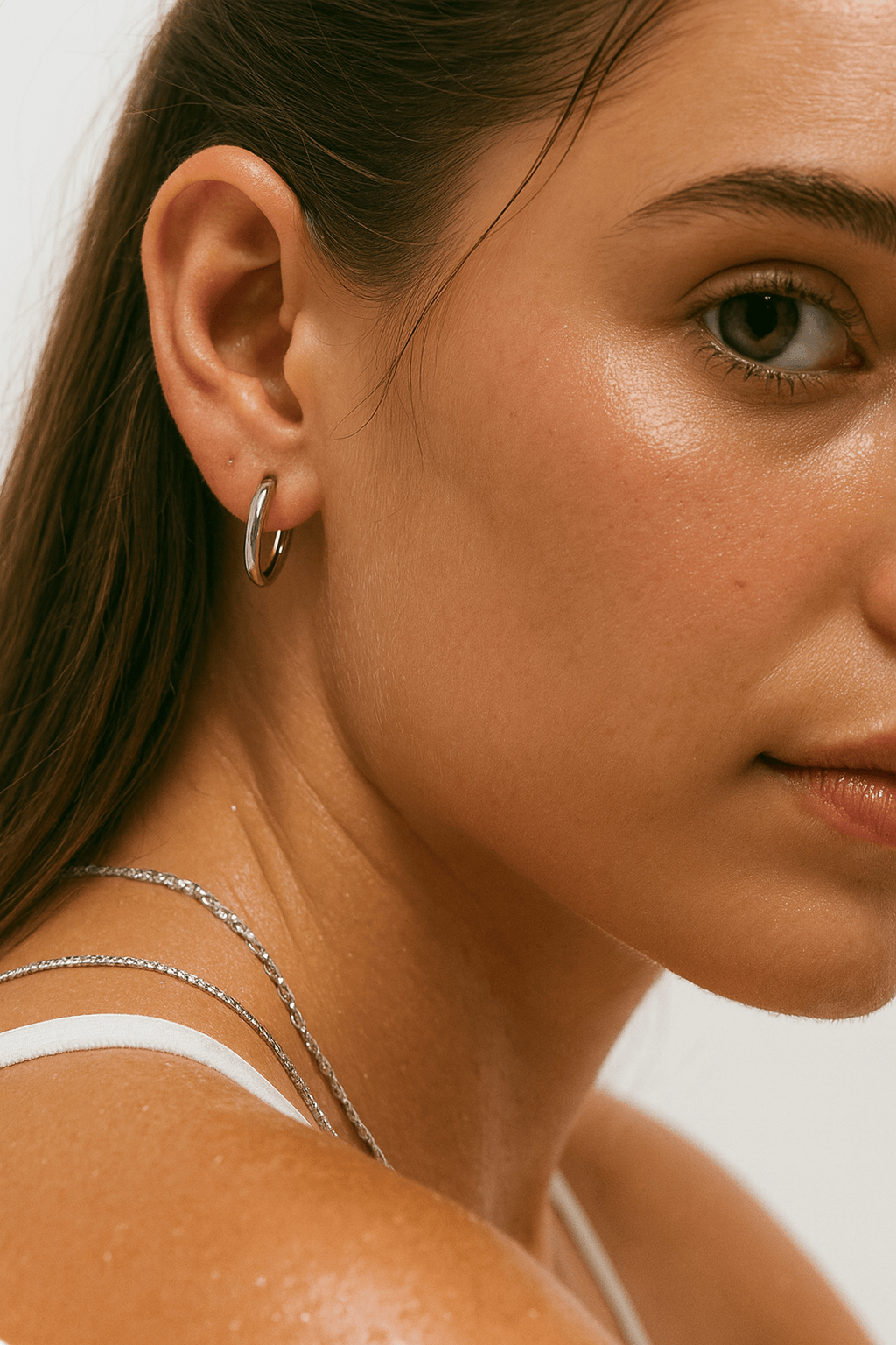 Close-up of a woman wearing a silver-plated hoop earring